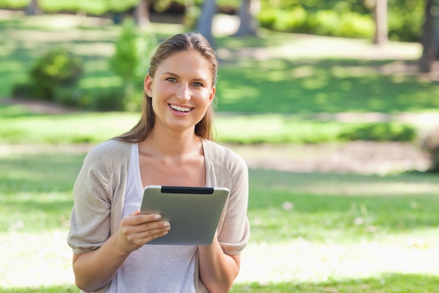 Mujer sonriente en el parque con su tableta