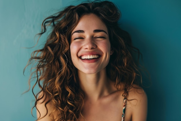 Mujer sonriente con pelo rizado y fondo azul.