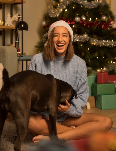 Foto mujer sonriente con perro posando con sombrero de santa