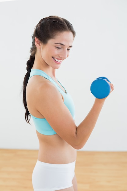 Mujer sonriente con pesas en el gimnasio