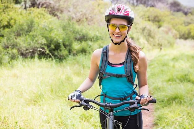 Mujer sonriente de pie junto a su bicicleta