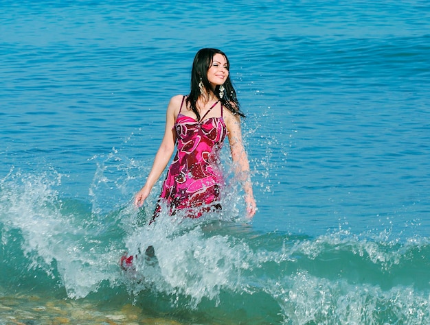 Mujer sonriente de pie en las olas del mar