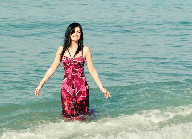 Mujer sonriente de pie en las olas del mar