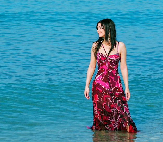 Mujer sonriente de pie en las olas del mar