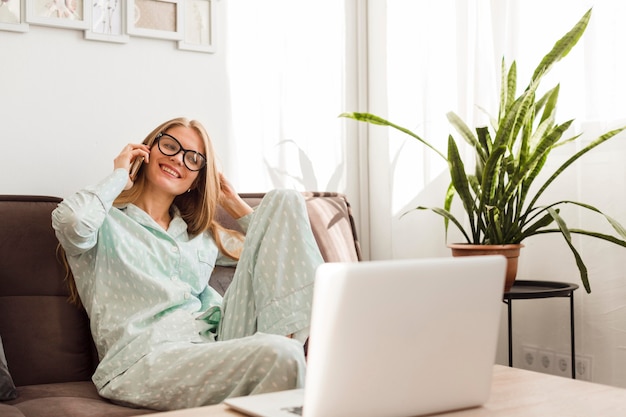 Mujer sonriente en pijama trabajando desde casa