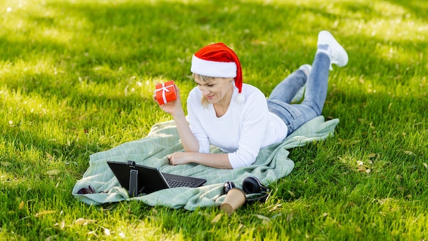 Mujer sonriente con portátil en el parque. Freelancer escribiendo en la computadora portátil