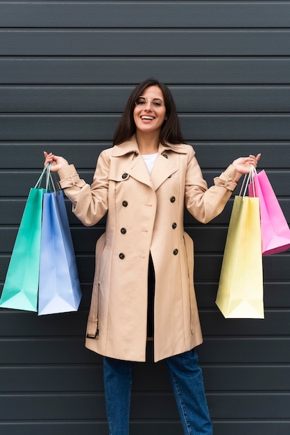 Foto mujer sonriente posando al aire libre y sosteniendo bolsas de la compra.