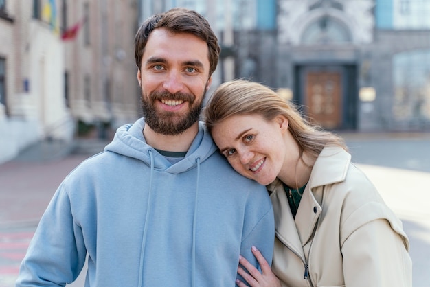 Foto mujer sonriente posando mientras se inclina contra un hombre al aire libre