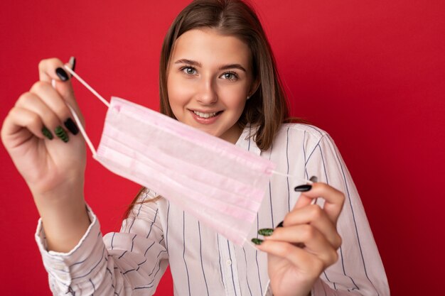 Mujer sonriente positiva con máscara protectora de virus contra el coronavirus y con bata médica blanca