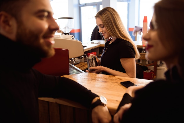 Mujer sonriente positiva que prepara el café en el contador. Concepto de modelo de personas reales