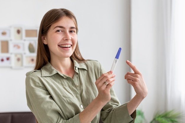 Mujer sonriente con prueba de embarazo