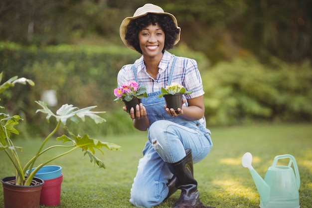 Mujer sonriente que se agacha en el jardín que sostiene las flores