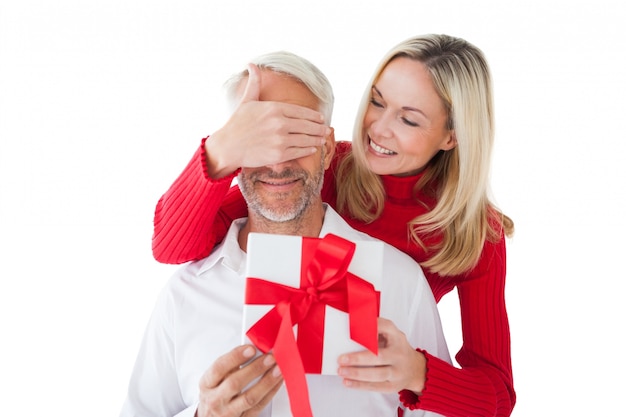 Mujer sonriente que cubre los ojos de los socios y la celebración de regalo