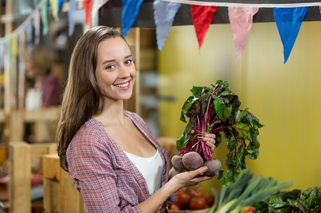 Mujer sonriente que elige verduras en supermercado