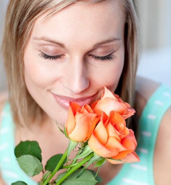 Mujer sonriente que huele rosas