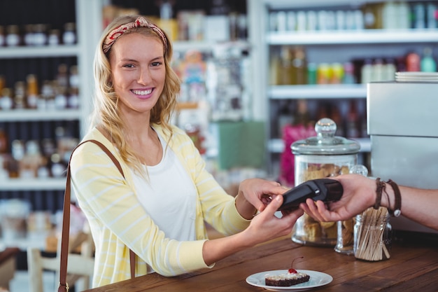 Mujer sonriente que ingresa el número pin en la máquina en el mostrador