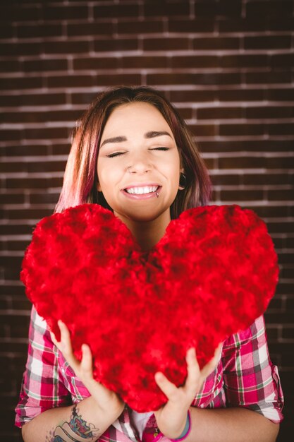 Foto mujer sonriente que lleva a cabo forma del corazón