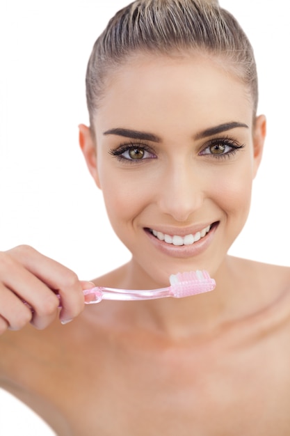 Mujer sonriente que sostiene un cepillo de dientes