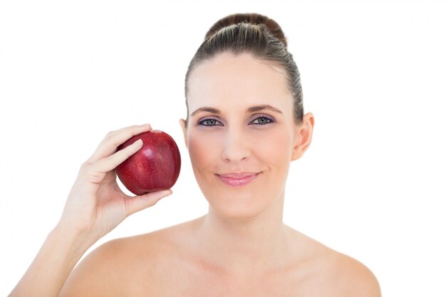 Mujer sonriente que sostiene la manzana roja que mira la cámara