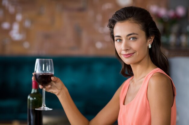 Mujer sonriente que sostiene el vidrio de vino tinto