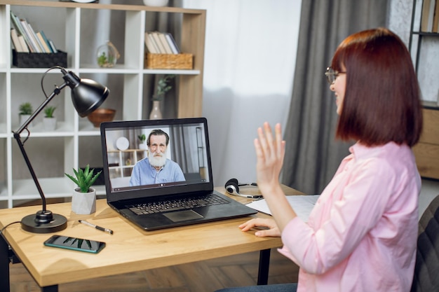 Mujer sonriente que tiene videollamada en la computadora portátil con el abuelo