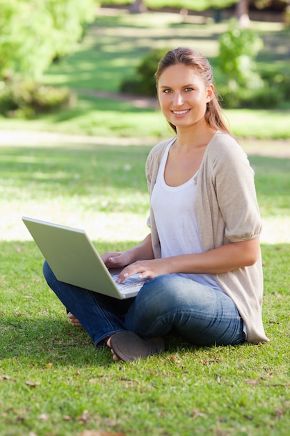 Mujer sonriente que trabaja en su cuaderno en el parque