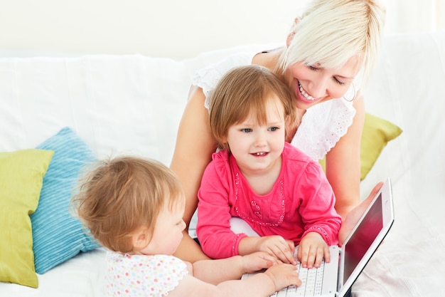 Mujer sonriente que trabaja con sus niños en la computadora portátil