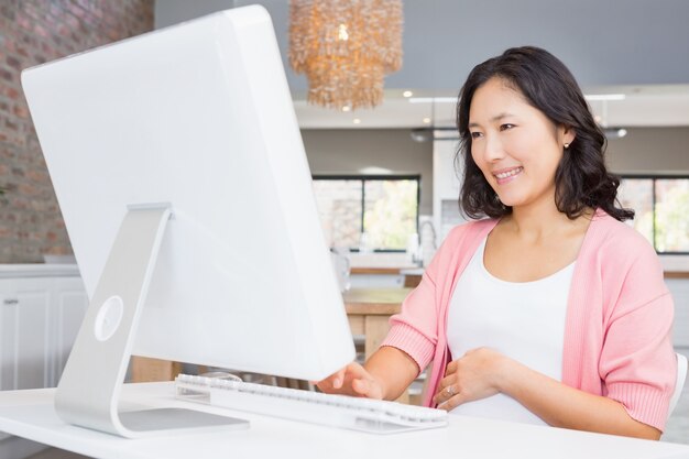 Mujer sonriente que usa la computadora en casa