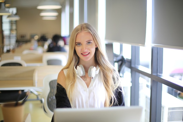 Una mujer sonriente que usa una computadora portátil en el lugar de trabajo para pequeñas empresas que buscan involucrar al público y la creación de contenido a escala puede adoptar nuevas tecnologías de marketing en el espacio de trabajo. Concepto de autónomo.