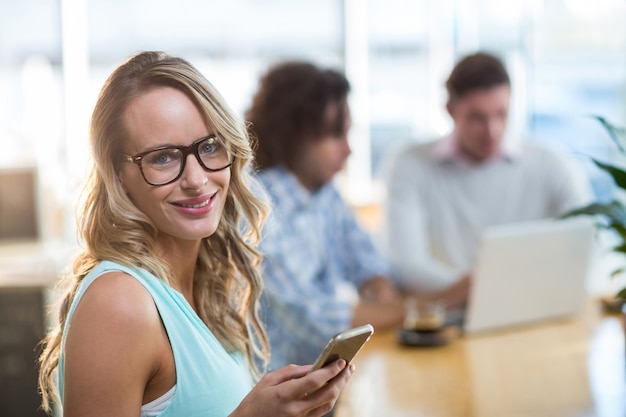 Mujer sonriente que usa el teléfono móvil en café