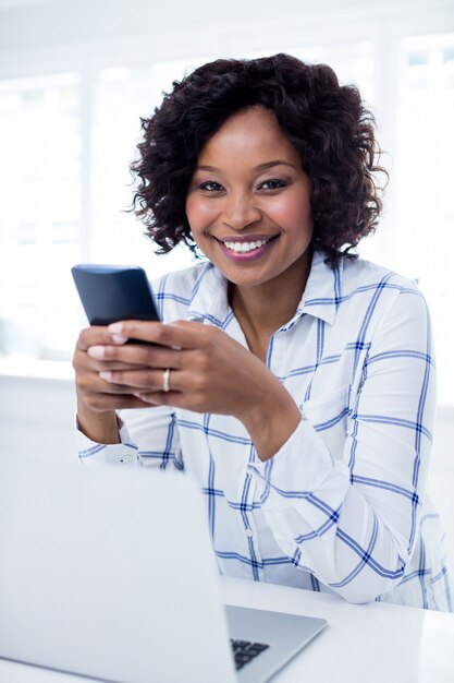 Mujer sonriente que usa el teléfono móvil en sala de estar