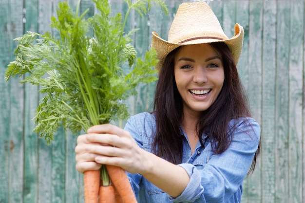 Mujer sonriente con racimo de zanahorias