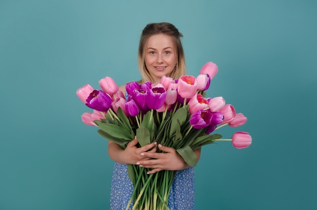 Mujer sonriente con el ramo de tulipanes rosados y púrpuras. Concepto de verano y primavera.