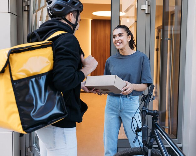 Foto mujer sonriente recibiendo un paquete del repartidor