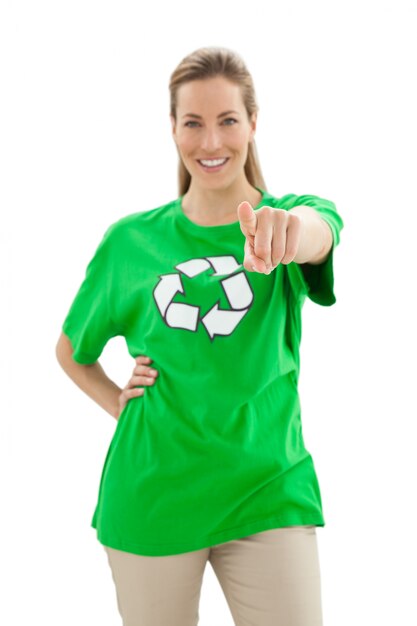 Mujer sonriente en el reciclaje de la camiseta del símbolo que señala en la cámara