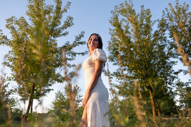 Mujer sonriente relajante en la naturaleza ángulo bajo