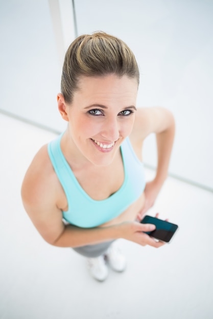 Mujer sonriente en ropa deportiva con teléfono móvil