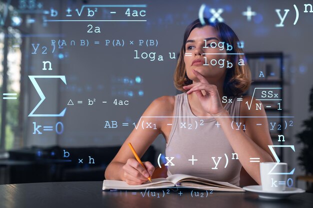 Foto mujer sonriente con ropa informal tomando notas en un cuaderno en el lugar de trabajo de la oficina con una taza de café concepto de educación empresarial distante tecnología de la información soñando pensando dibujos matemáticos