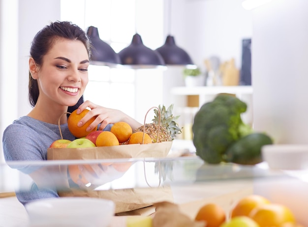 Mujer sonriente sacando una fruta fresca de la nevera concepto de comida saludable