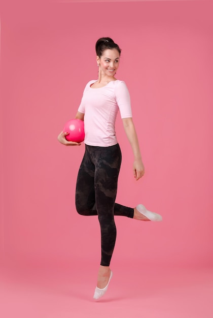 Mujer sonriente saltando con la pelota