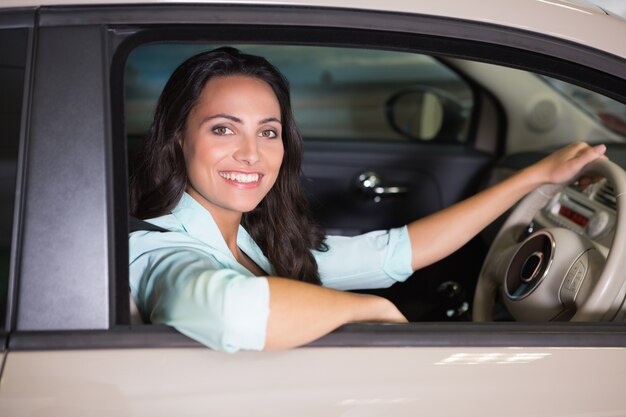 Foto mujer sonriente sentada al volante de su coche nuevo