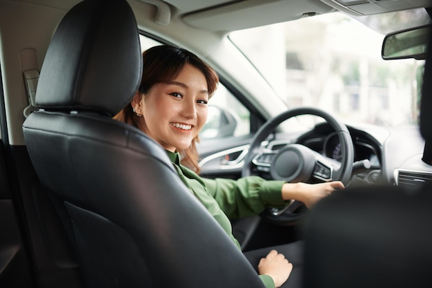 Mujer sonriente sentada en un coche y mirando hacia atrás