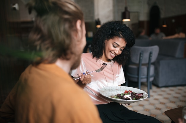 Mujer sonriente sentada en un restaurante con un amigo