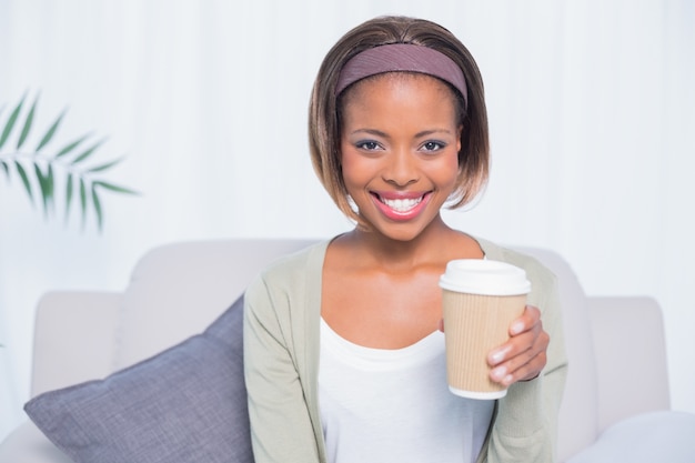 Mujer sonriente sentada en el sofá con café