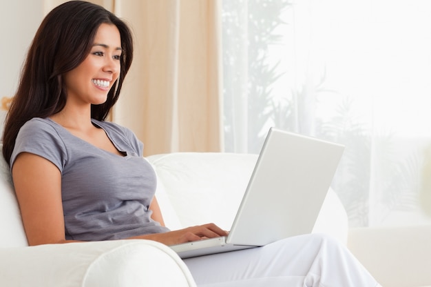 mujer sonriente sentada en el sofá con el cuaderno