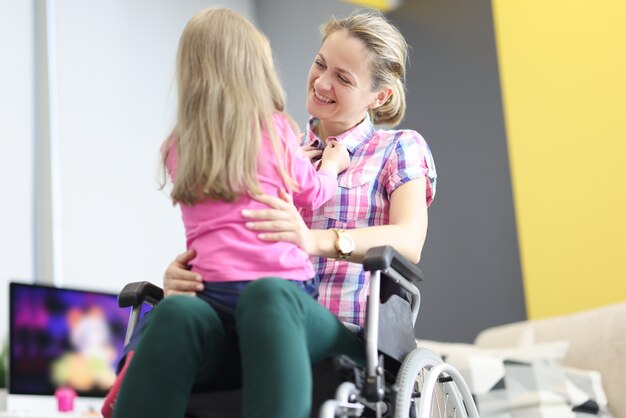 Mujer sonriente en silla de ruedas abraza a niña