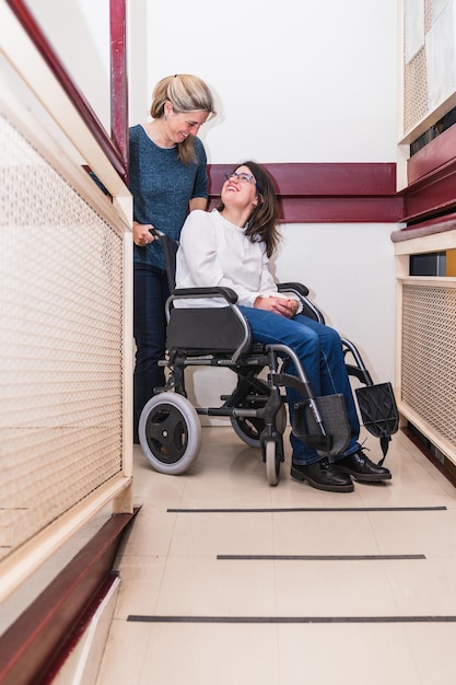 Una mujer sonriente en silla de ruedas comparte un momento con un ayudante