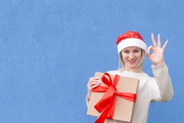 Una mujer sonriente con un sombrero de Año Nuevo con un regalo en sus manos Fiestas y eventos Navidad