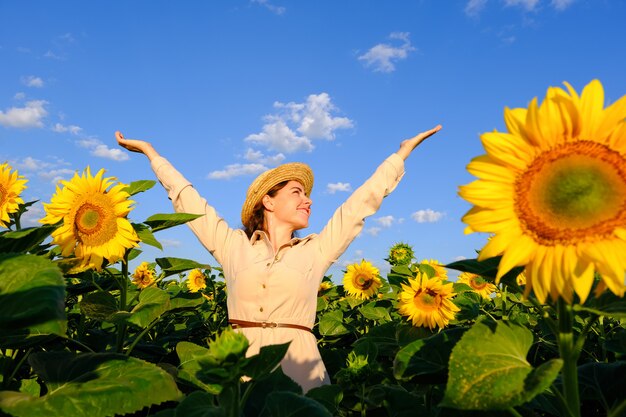 Mujer sonriente en sombrero de paja en campo floreciente del girasol