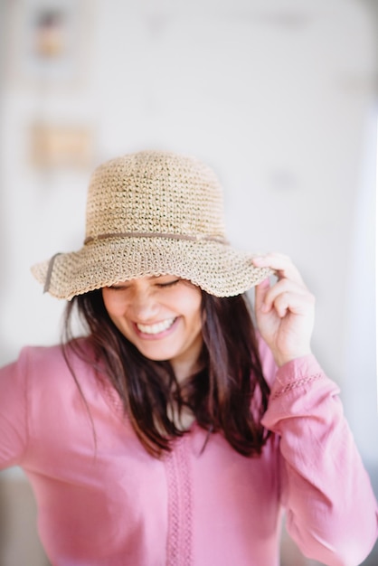 Foto mujer sonriente con sombrero de pie en el interior